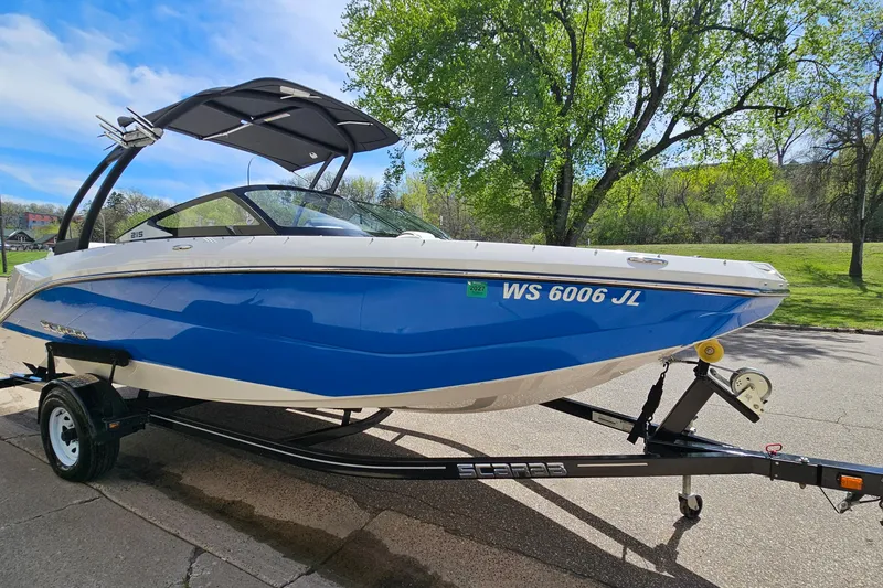 Slide: The Image of 2014 Scarab 215 boat in blue and white on a trailer, parked outdoors. - 3
