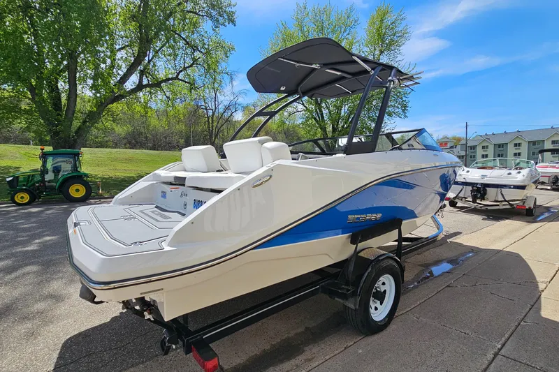 Slide: The Image of 2014 Scarab 215 boat on trailer, parked outdoors with trees and buildings in background. - 4