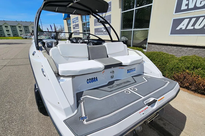 Slide: The Image of 2014 Scarab 215 boat with white seating, displayed outdoors near a dealership. - 6