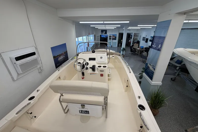 Slide: The Image of 2026 Scout 188 Sportfish boat interior in showroom, featuring steering console and seating. - 2