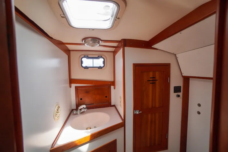 Slide: The Image of Interior of 2001 Redfern Mitchell Cove 32 boat, featuring a compact bathroom with wooden accents. - 27