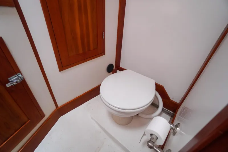 Slide: The Image of Boat bathroom interior with wooden accents, featuring a toilet and toilet paper holder. Redfern Mitchell Cove 32, 2001. - 28