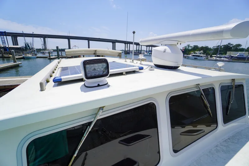 Slide: The Image of 2001 Redfern Mitchell Cove 32 boat with solar panels and radar, docked near a bridge. - 34