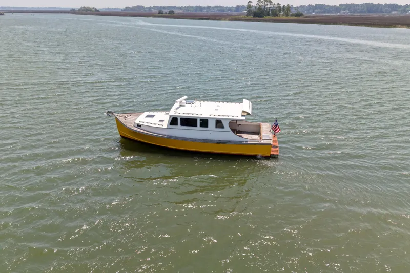 Slide: The Image of Yellow Redfern Mitchell Cove 32 boat from 2001 on calm water, American flag displayed. - 4