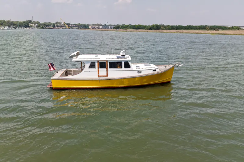 Slide: The Image of Yellow Redfern Mitchell Cove 32 boat from 2001 on calm water with American flag. - 9