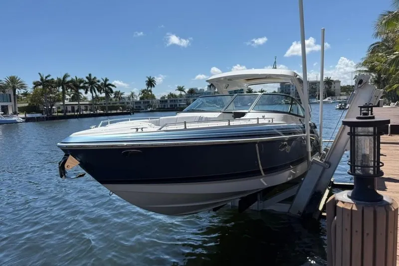 Slide: The Image of 2025 Formula 330 Crossover Bowrider OB docked by a scenic waterfront. - 2