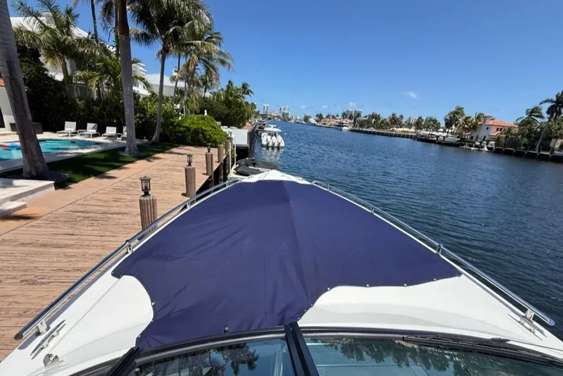 Slide: The Image of 2025 Formula 330 Crossover Bowrider OB docked by a scenic waterfront with palm trees. - 75