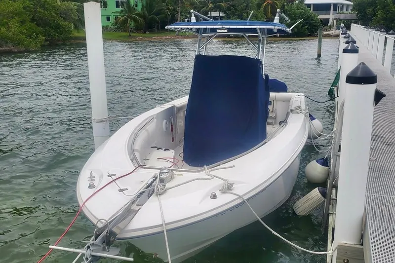 Slide: The Image of 2004 Boston Whaler 270 Outrage docked by a waterfront with lush greenery. - 14