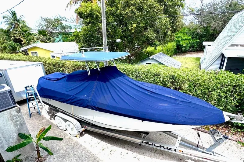 Slide: The Image of 2004 Boston Whaler 270 Outrage boat covered with blue tarp on trailer. - 15