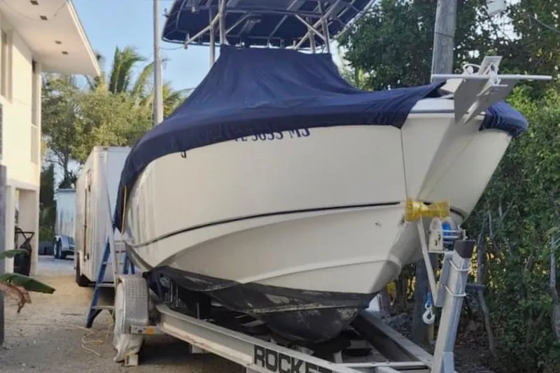 Slide: The Image of 2004 Boston Whaler 270 Outrage boat on trailer, covered, parked outdoors. - 16
