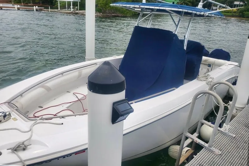 Slide: The Image of 2004 Boston Whaler 270 Outrage docked, featuring blue covers and a T-top canopy. - 18