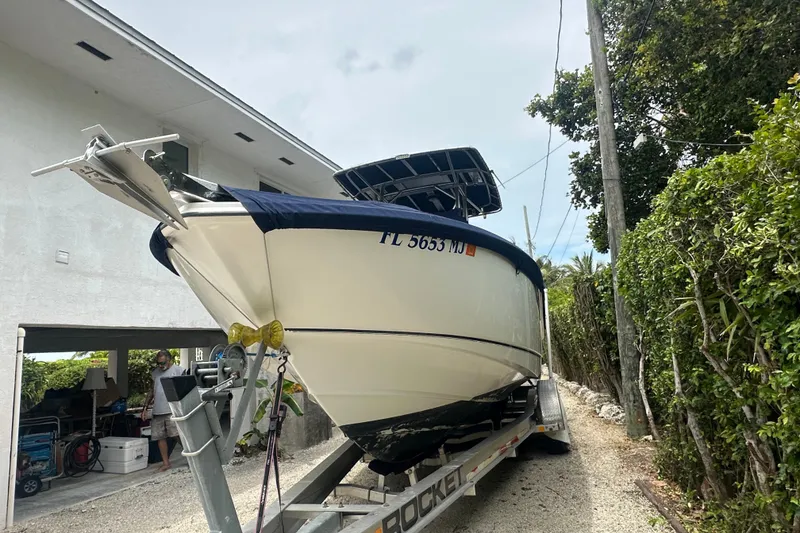 The Image of 2004 Boston Whaler 270 Outrage boat on trailer, parked beside a house. - 6