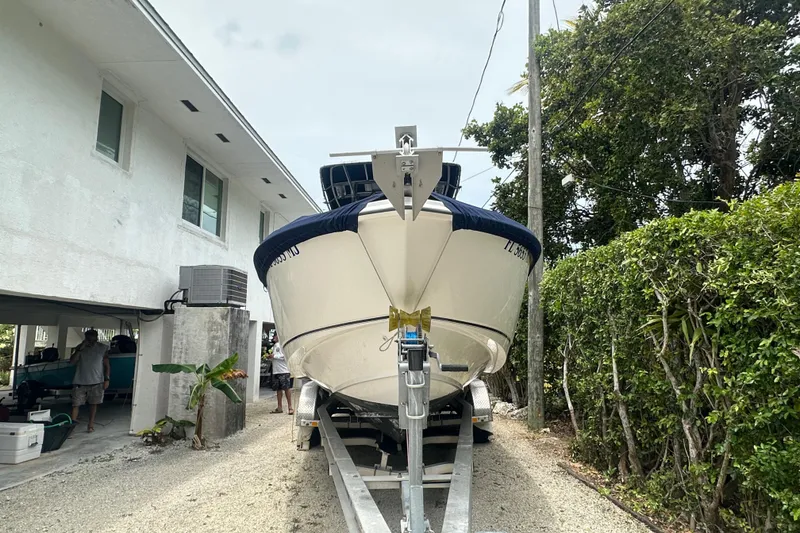 Slide: The Image of 2004 Boston Whaler 270 Outrage boat on trailer near house and greenery. - 8