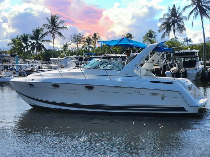 The Image of 2002 Formula 31 PC boat docked, surrounded by palm trees and a vibrant sunset sky. - 0