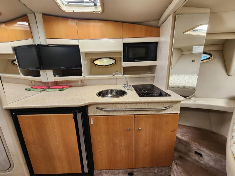 Slide: The Image of 2002 Formula 31 PC yacht interior with kitchenette, featuring sink, stove, and compact fridge. - 10