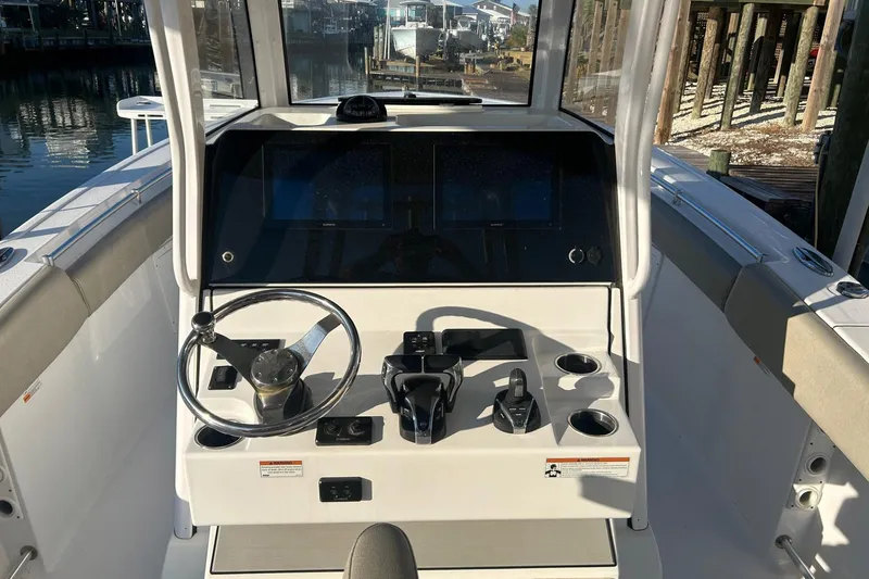 Slide: The Image of 2022 Sportsman Open 282TE Center Console boat dashboard with steering wheel and controls. - 1