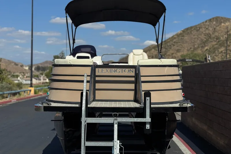 Slide: The Image of 2023 Lexington 623 ST Xtreme pontoon boat on trailer, scenic mountain backdrop. - 2