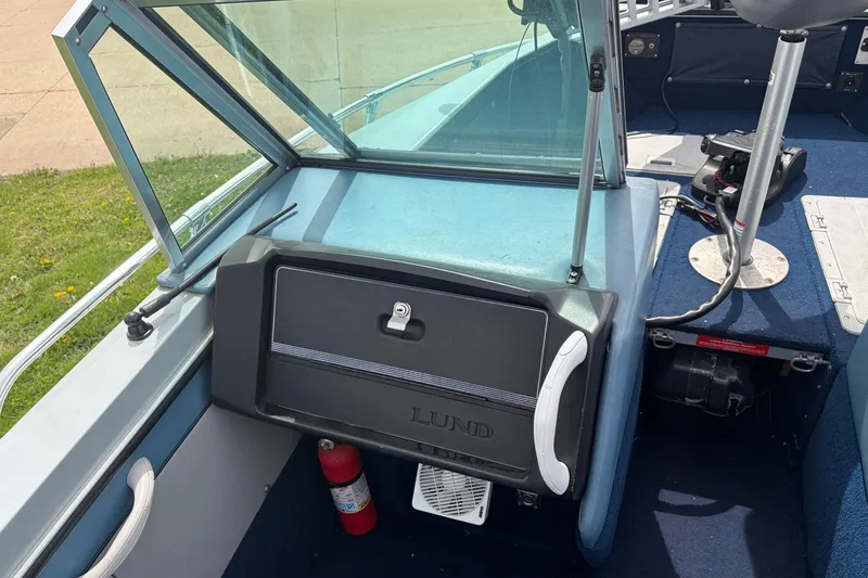 Slide: The Image of 1991 Lund 1750 Tyee boat interior with windshield, storage compartment, and fire extinguisher. - 10