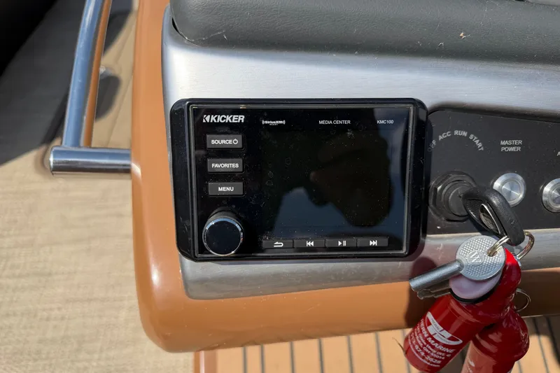 Slide: The Image of Kicker media center on 2020 Regency 250 LE3 Sport boat dashboard with keys. - 2