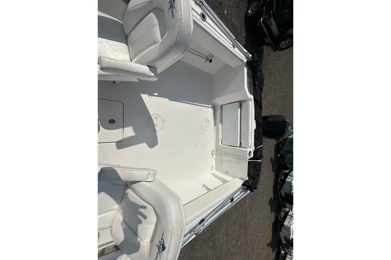 Slide: The Image of 2024 Aquasport 2200 Dual Console boat interior with white seating and storage compartments. - 19
