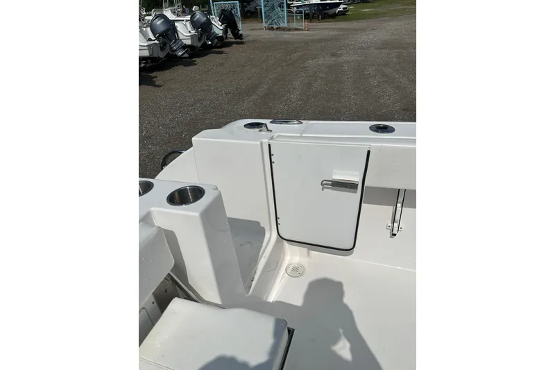 Slide: The Image of 2024 Aquasport 2200 Dual Console boat interior with cup holders and storage compartment. - 24