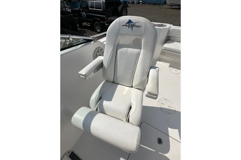 Slide: The Image of 2024 Aquasport 2200 Dual Console boat seat with logo, featuring white upholstery and armrests. - 33