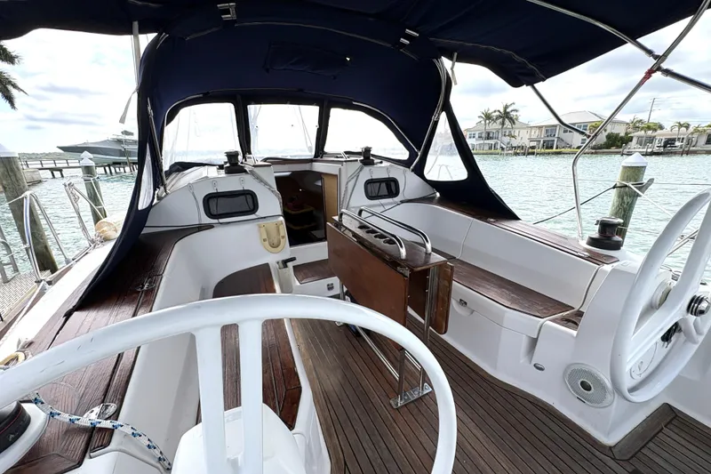 Slide: The Image of 2018 Elan Impression yacht cockpit with wooden deck and steering wheel, docked by the water. - 6