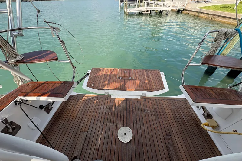 Slide: The Image of 2018 Elan Impression yacht deck with wooden finish, overlooking calm marina waters. - 9