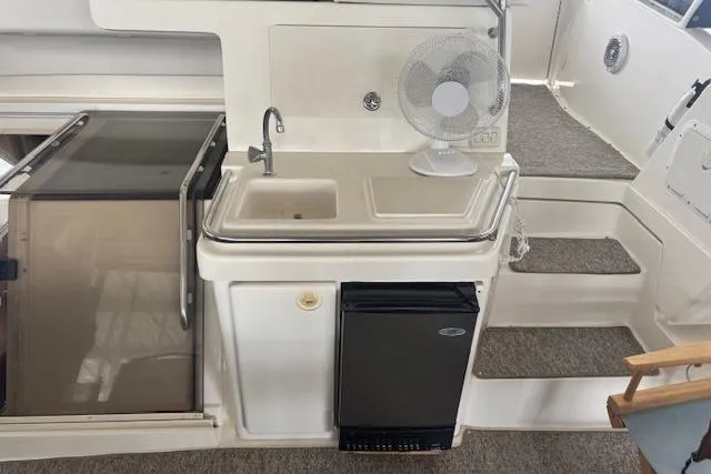 Slide: The Image of 1998 Silverton 372 Motor Yacht interior with sink, mini fridge, and fan. - 11