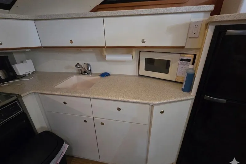 Slide: The Image of 1998 Silverton 372 Motor Yacht kitchen with sink, microwave, and cabinets. - 24