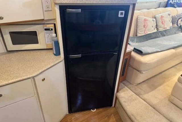 Slide: The Image of 1998 Silverton 372 Motor Yacht interior with fridge, microwave, and seating area. - 25