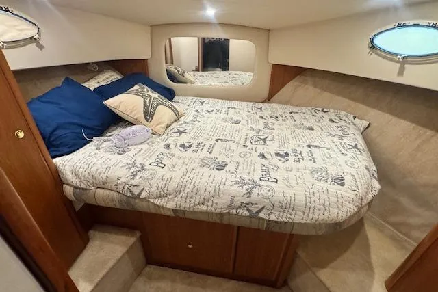 Slide: The Image of 1998 Silverton 372 Motor Yacht cabin with cozy bed, nautical-themed bedding, and porthole window. - 35