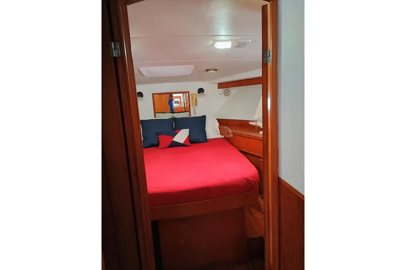 Slide: The Image of 1988 Vantare 46' Aft Cabin Wide Body MY bedroom with red bedding and wooden interior. - 26