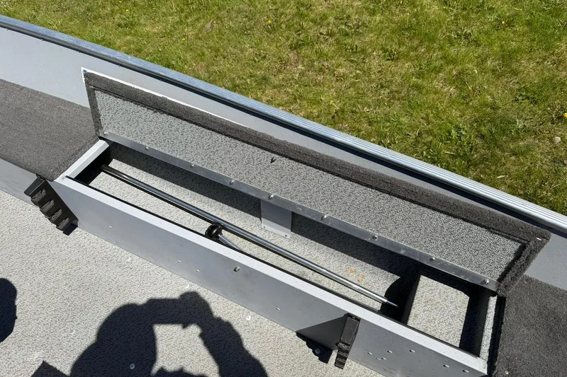 Slide: The Image of Open storage compartment in a 2013 Lund 1600 Fury Tiller boat, grassy background. - 15