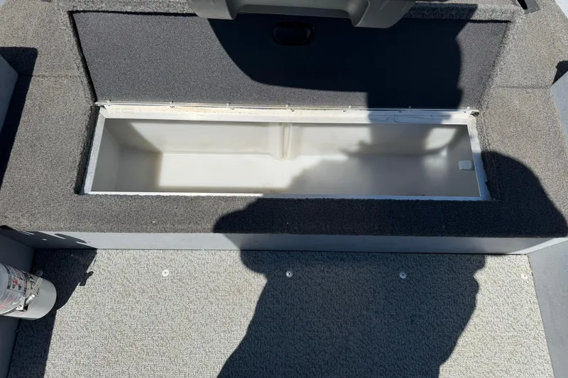 Slide: The Image of Open storage compartment in 2013 Lund 1600 Fury Tiller boat, with gray carpeted interior. - 16