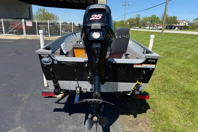 Slide: The Image of 2013 Lund 1600 Fury Tiller boat with 25 HP motor, parked outdoors. - 3