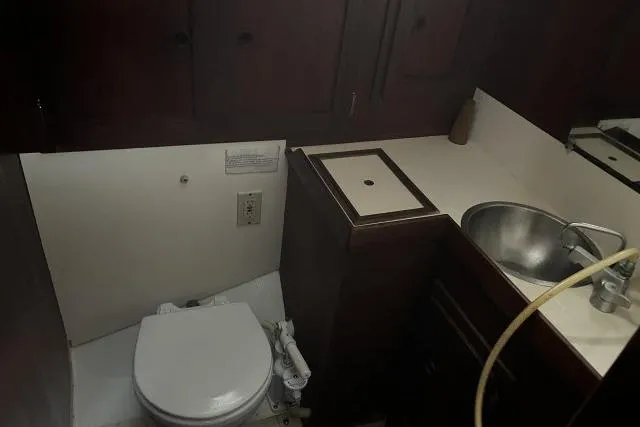 Slide: The Image of 1977 Uniflite Valiant 40 yacht bathroom with sink, toilet, and wooden cabinetry. - 19