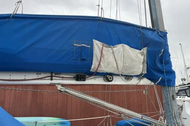 Slide: The Image of 1977 Uniflite Valiant 40 sailboat with blue sail cover, docked against a wooden wall. - 36