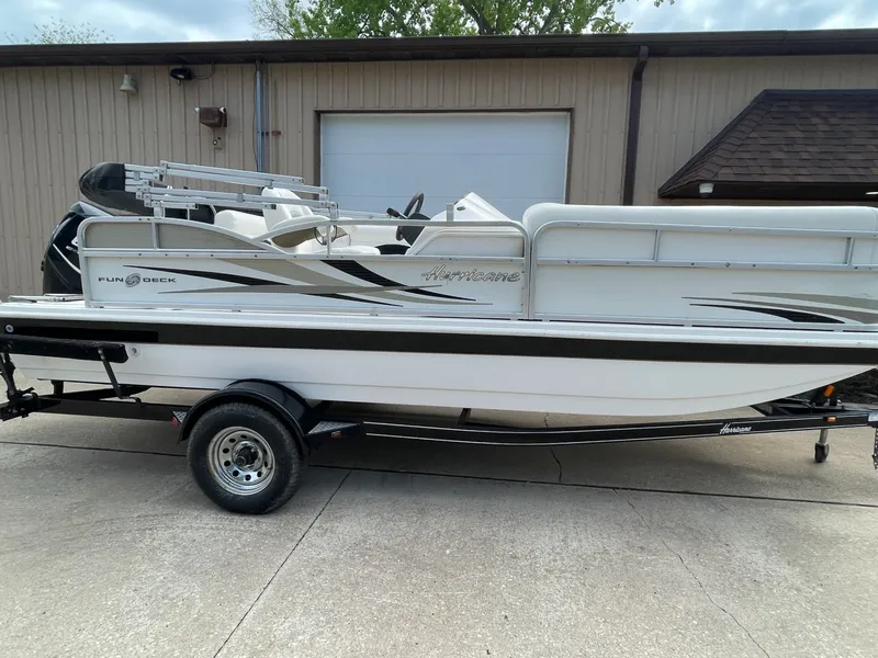 The Image of 2010 Hurricane FD196 pontoon boat on trailer in front of garage. - 1