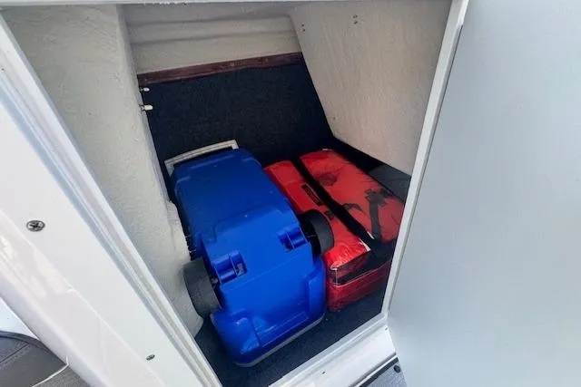Slide: The Image of Storage compartment in a 2021 Yamaha AR 210 boat with blue and red gear. - 19