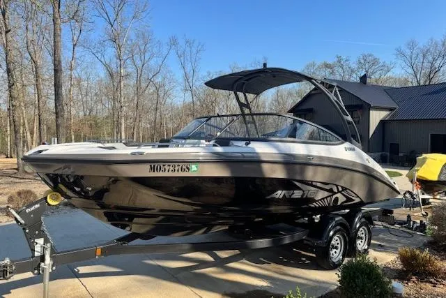Slide: The Image of 2021 Yamaha AR 210 boat on trailer in wooded driveway setting. - 2