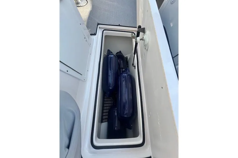 Slide: The Image of Storage compartment on a 2021 Yamaha AR 210 boat with blue fenders inside. - 26