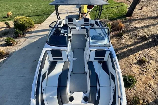 Slide: The Image of 2021 Yamaha AR 210 boat with spacious seating and canopy, parked on a driveway. - 27