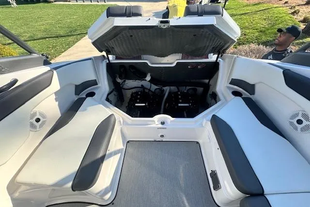 Slide: The Image of 2021 Yamaha AR 210 boat interior with open engine compartment, showcasing seating and speakers. - 30