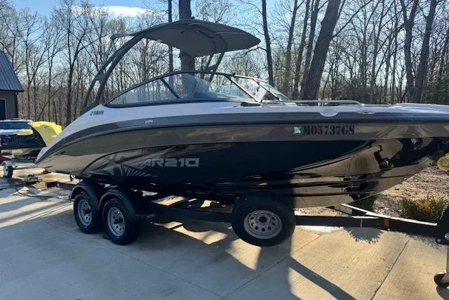 Slide: The Image of 2021 Yamaha AR 210 boat on trailer, parked outdoors in a wooded area. - 6