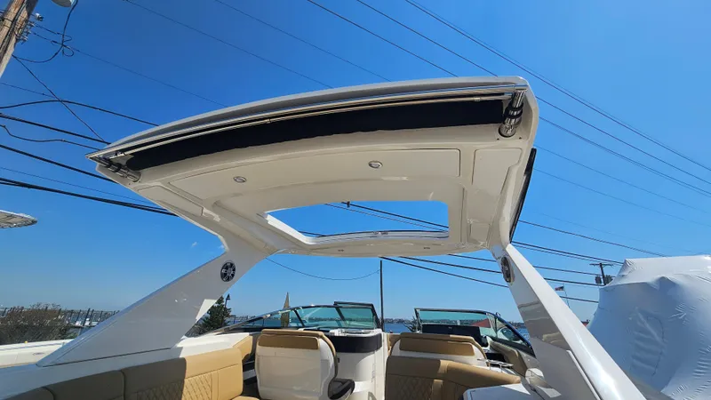 Slide: The Image of 2023 Sea Ray SLX 310 Outboard with open roof and blue sky. - 17