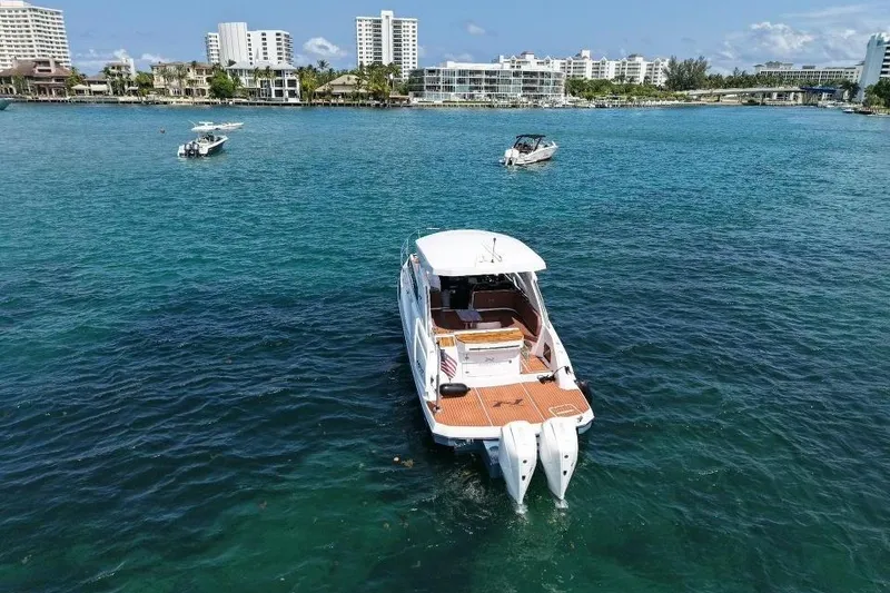 Slide: The Image of 2025 NX Boats 340 Sport Coupe on clear blue water near city skyline. - 10