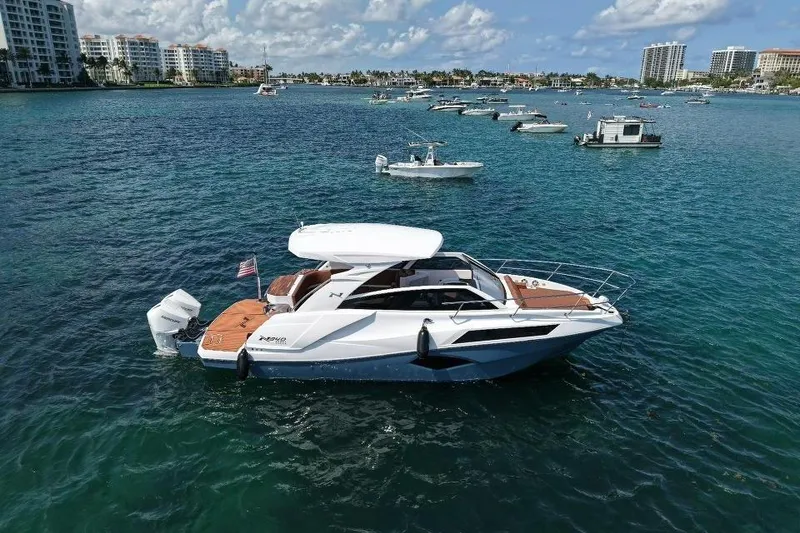 Slide: The Image of 2025 NX Boats 340 Sport Coupe cruising in a scenic marina with multiple boats. - 11