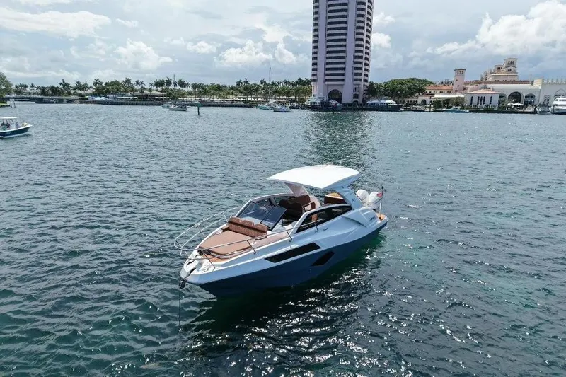 Slide: The Image of 2025 NX Boats 340 Sport Coupe cruising in a scenic marina setting. - 14