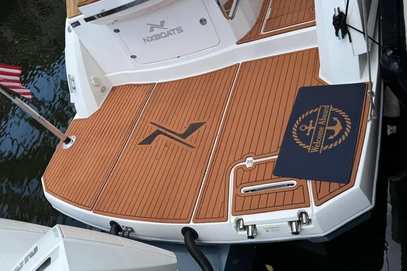 Slide: The Image of 2025 NX Boats 340 Sport Coupe with teak deck and "Welcome Aboard" mat. - 16